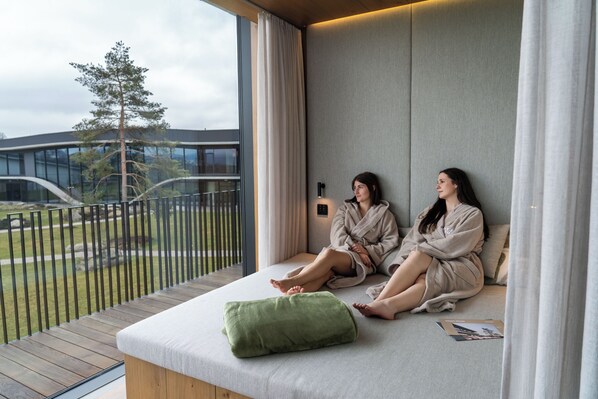 A modern room with a large window, a green pillow, and a magazine on the floor.