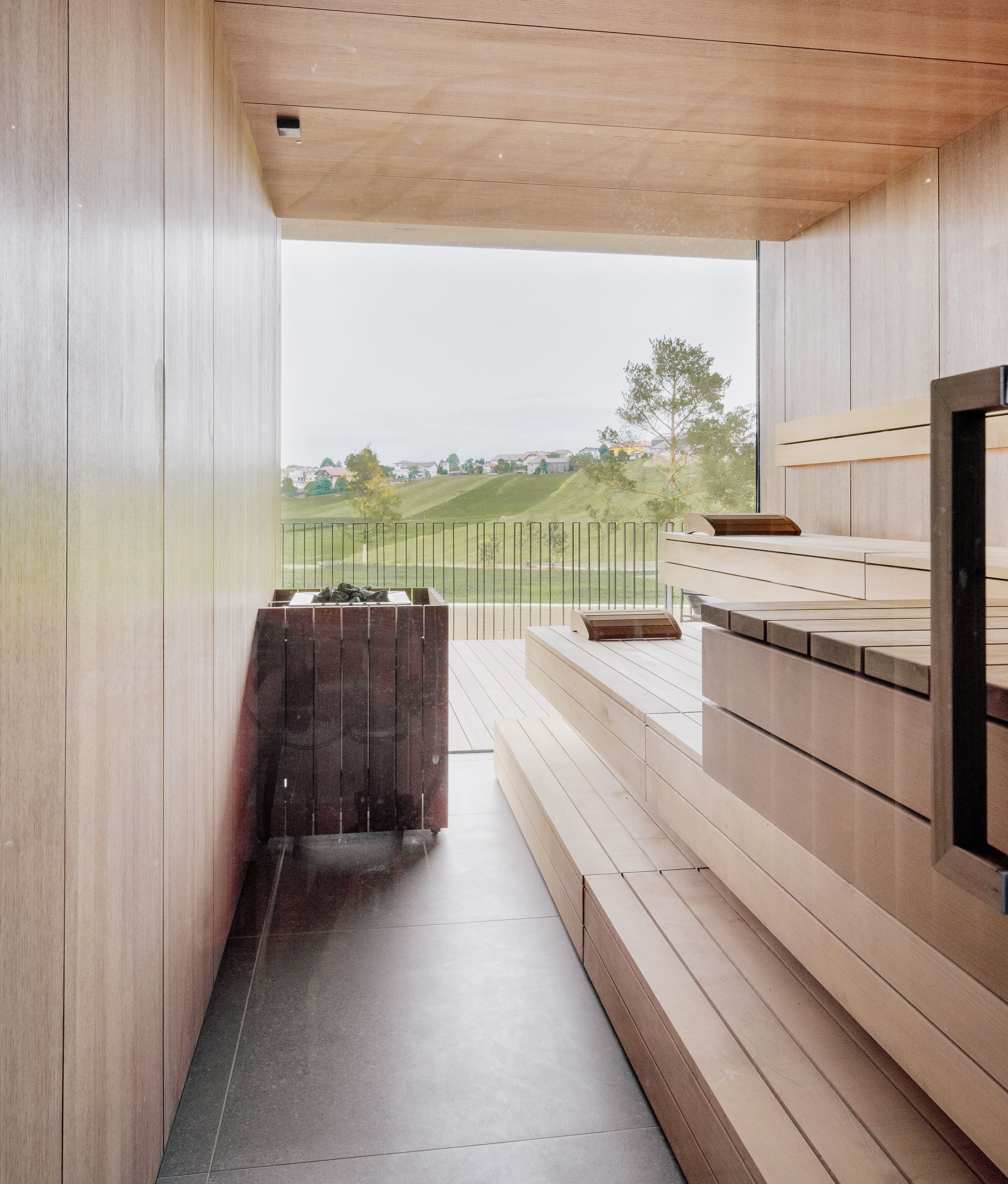 Een modern interieur met houten lambrisering, een ingebouwde bank en uitzicht op een groen landschap.