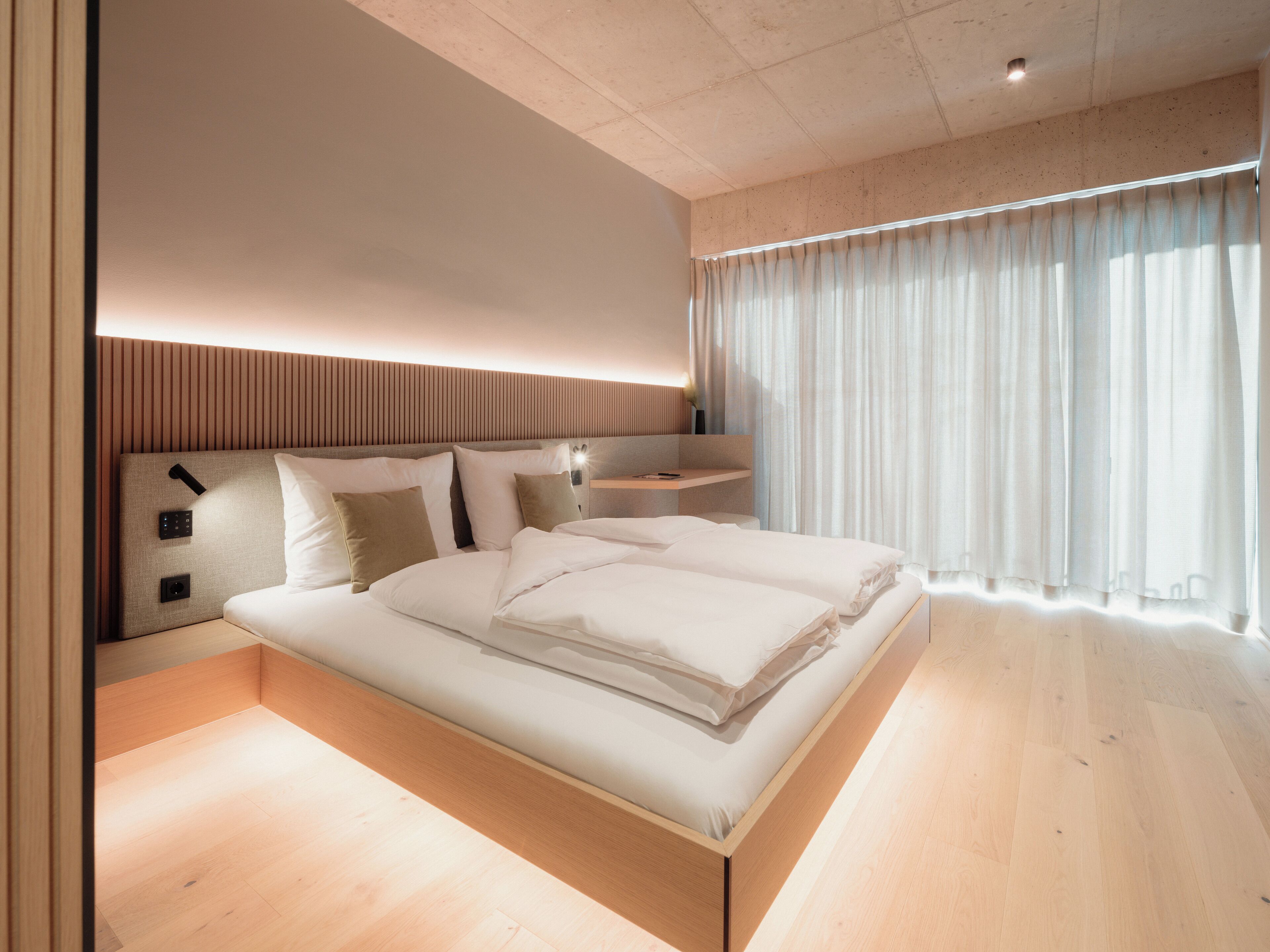 A modern bedroom with a large bed, bedside tables, and a nightstand.