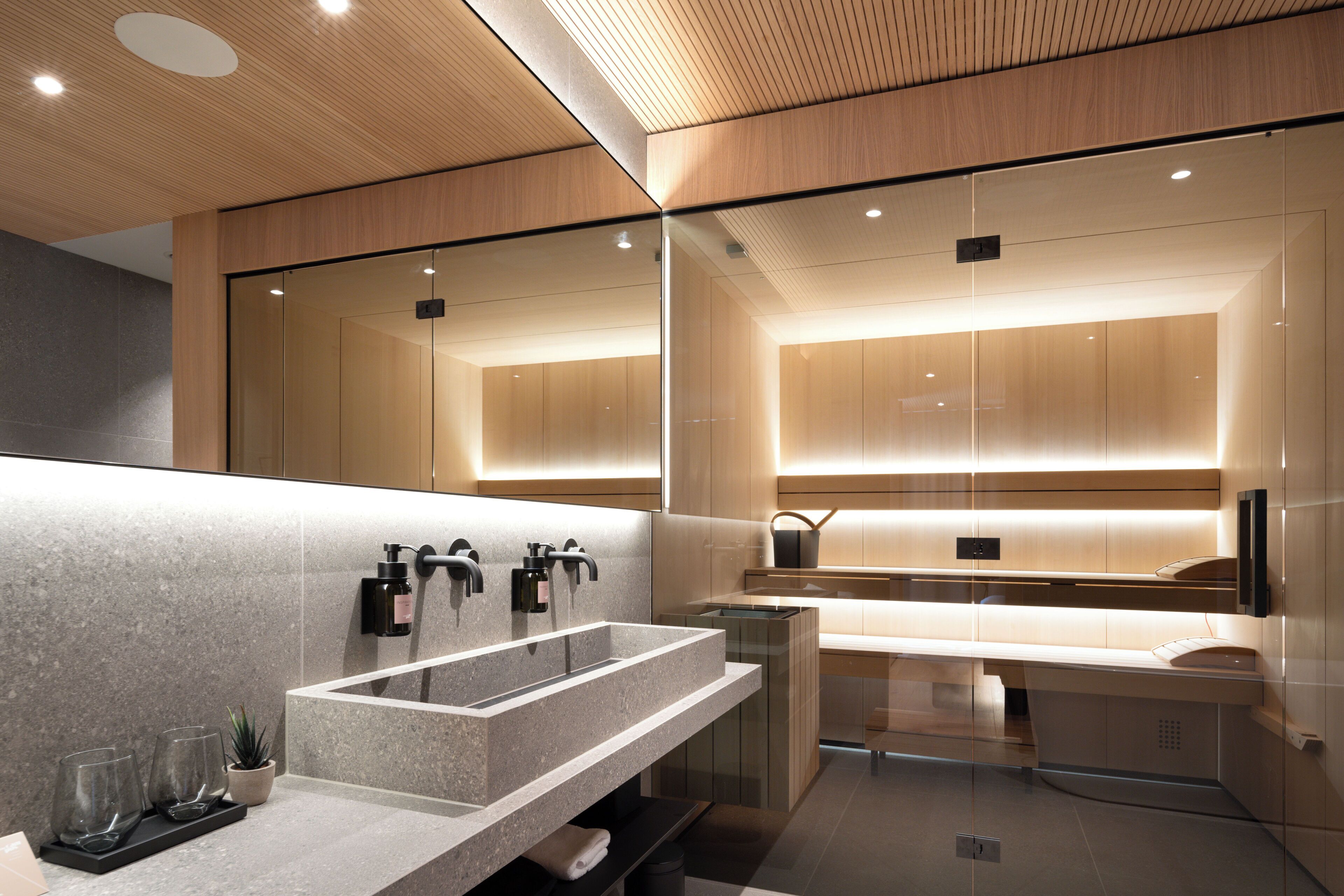 A modern bathroom with a large mirror, a granite sink, and a glass shower enclosure.