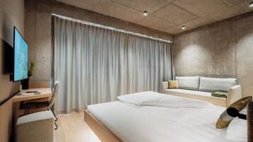 Et moderne hotelværelse med en stor seng, et skrivebord, en sofa og et fjernsyn.