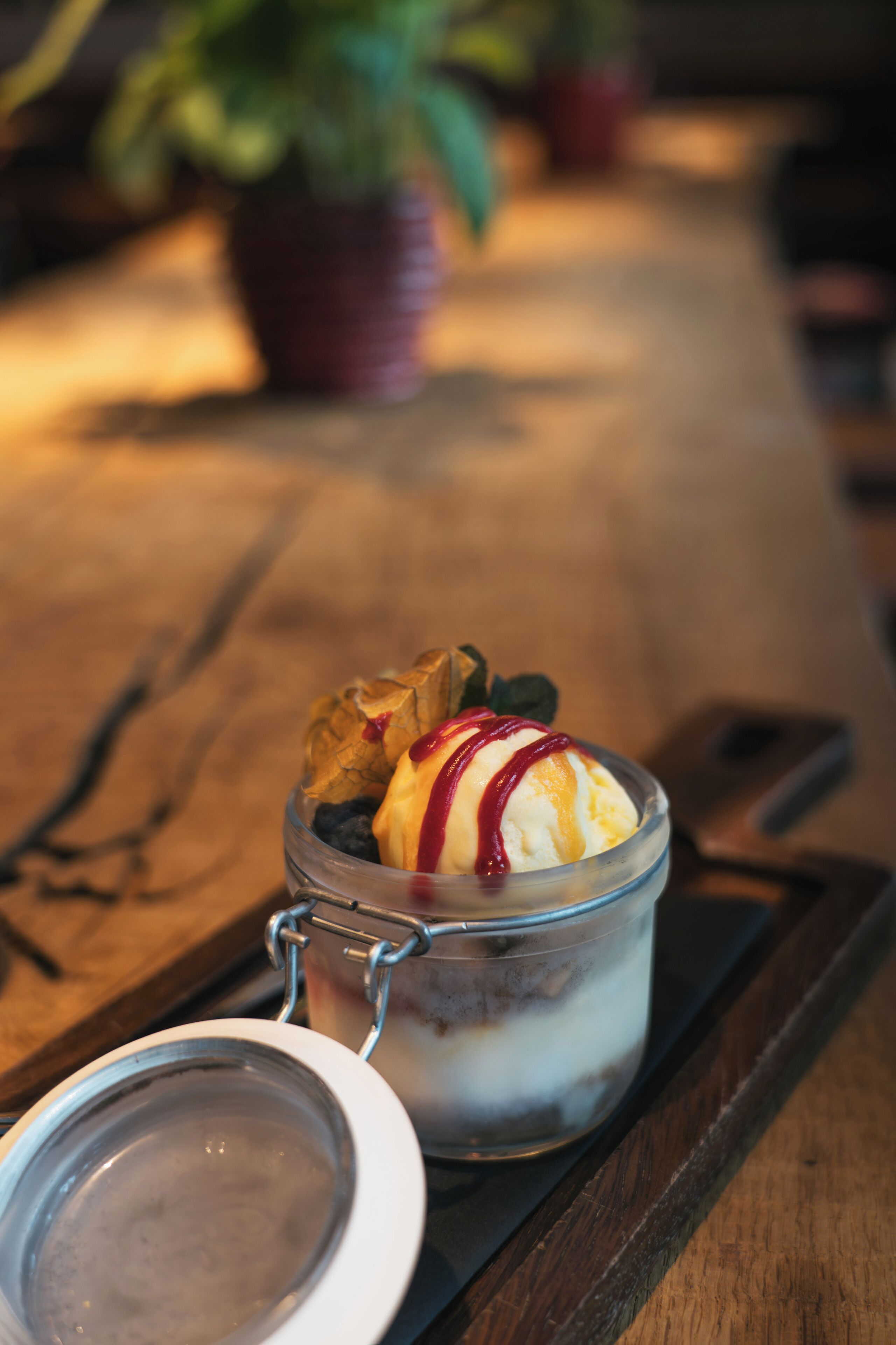 A dessert in a glass jar with a metal clasp lid, placed on a wooden surface.