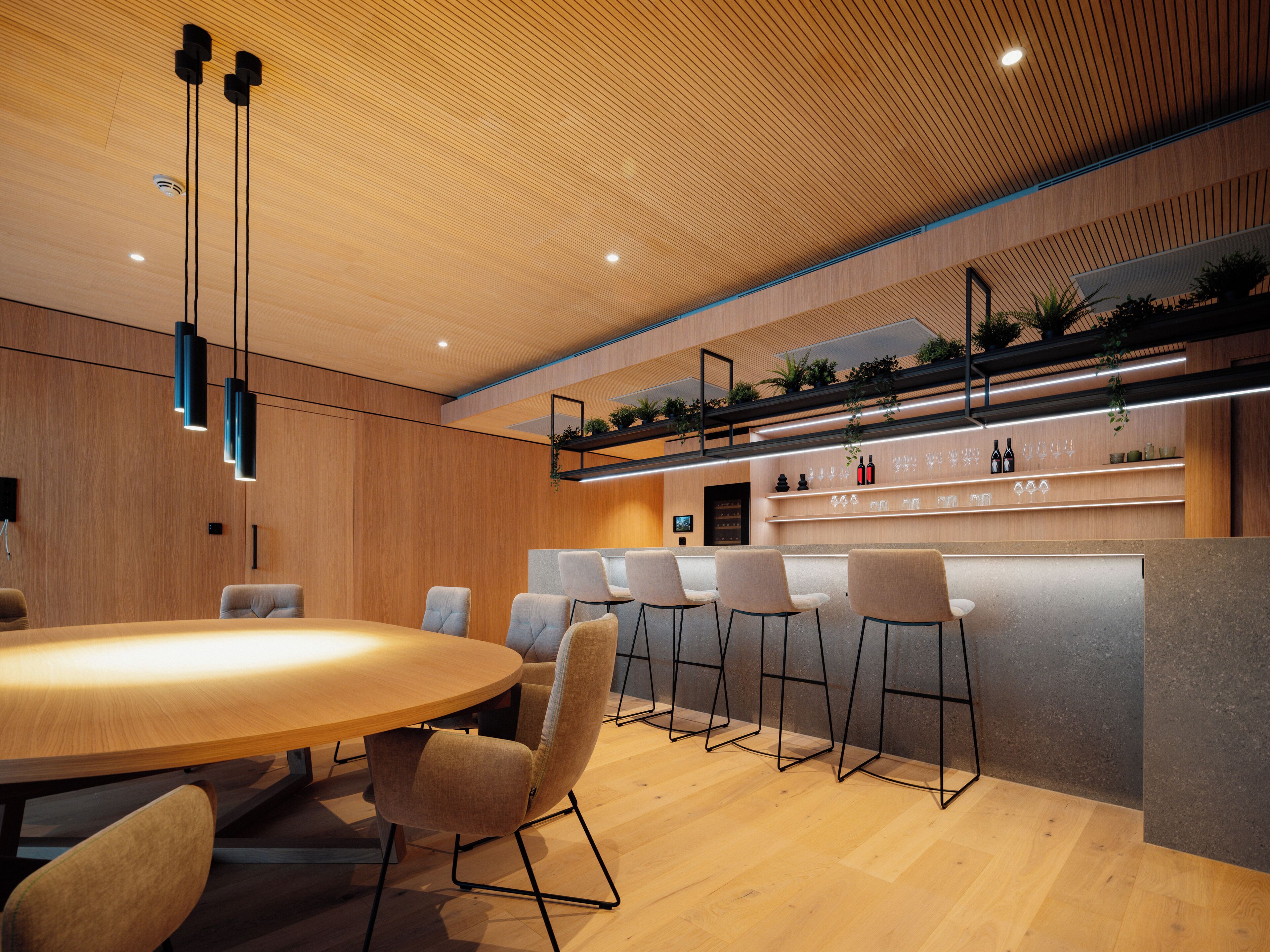 A modern kitchen with a wooden ceiling, bar area, and seating.