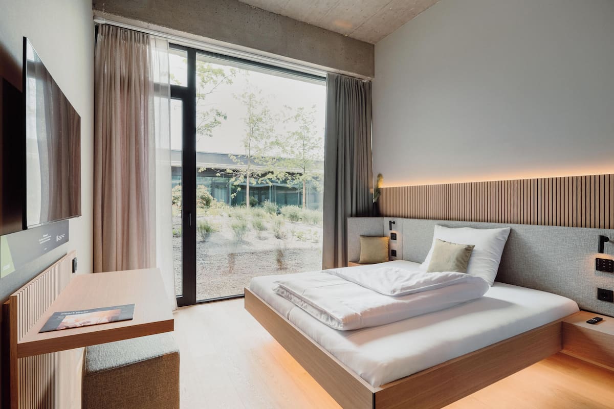 A modern hotel room with a large bed, a desk, and a television.