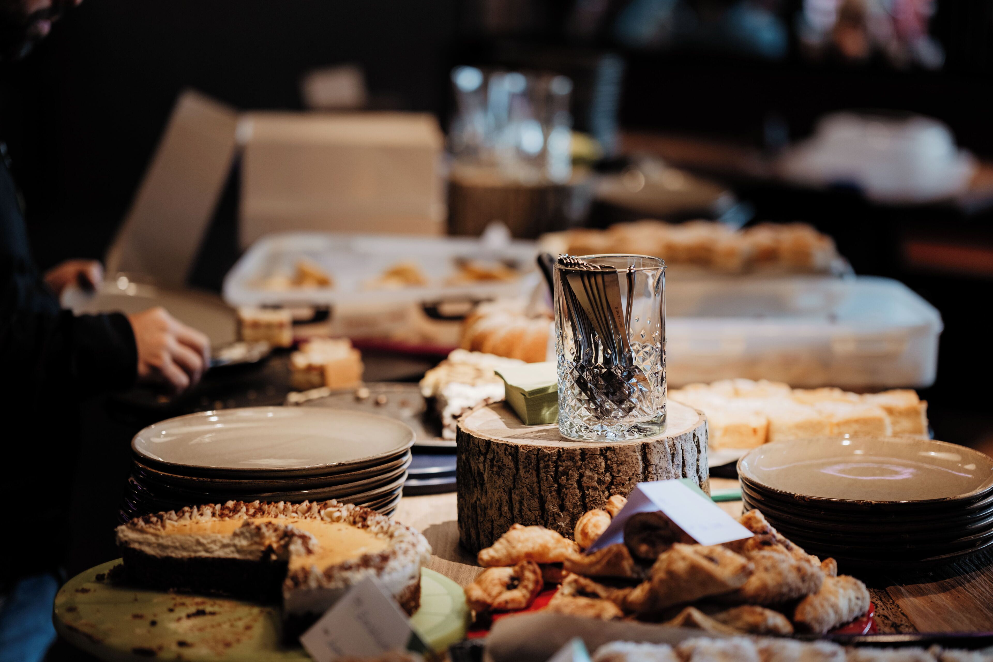 A buffet table with various food items and plates.