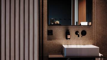 Un bany modern amb un lavabo rectangular, un mirall i una petita planta en test.