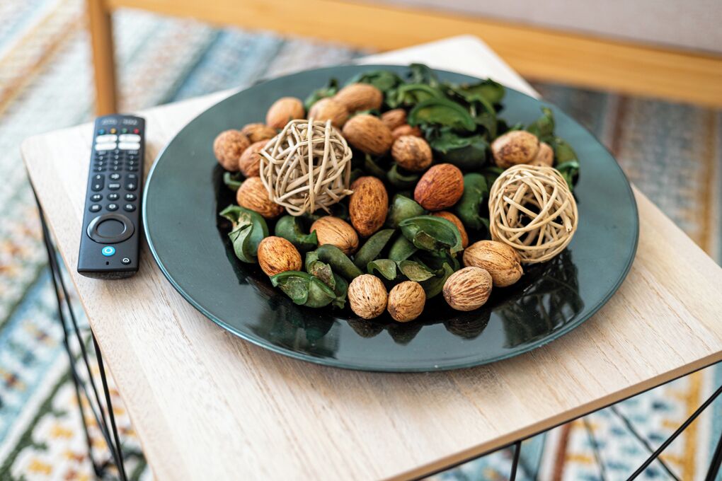 A plate of food with nuts and greens on a table next to a remote control.