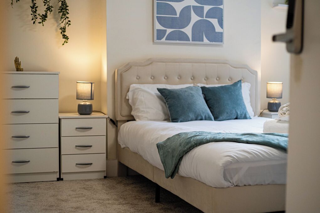 A bedroom with a bed, bedside tables, a dresser, and a wall art piece.