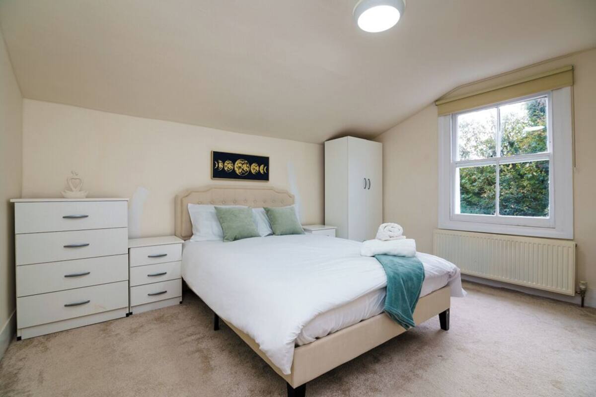 Une chambre à coucher comprenant un lit, une commode, un placard et une fenêtre donnant sur un paysage verdoyant.