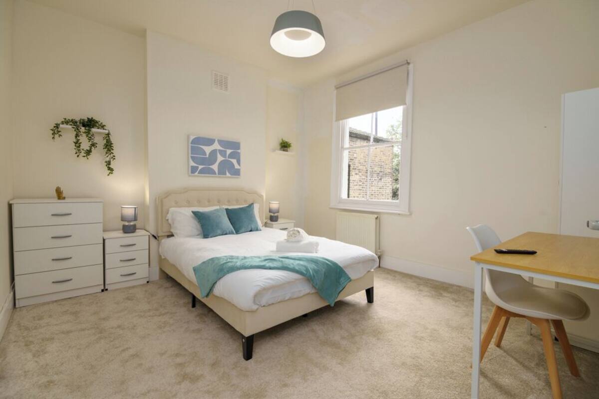 Une chambre à coucher avec un lit, des tables de chevet, un bureau et une chaise.
