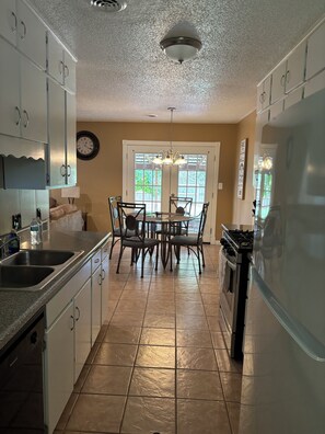 A kitchen with a dining table, chairs, a refrigerator, a stove, and a sink. - Convenient, and Clean Home 1BR (Springdale)