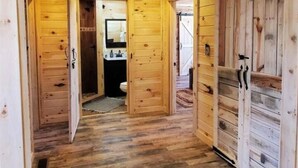 A wooden hallway with a wooden floor, a door leading to a bathroom, and a sign that says "home".
