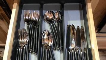 A drawer containing a set of black cutlery including forks, spoons, and knives.