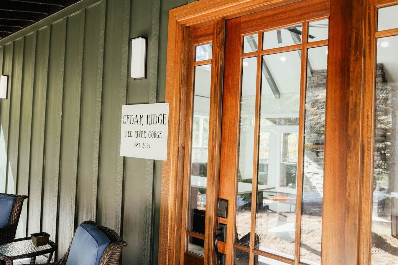 Une porte en bois avec une plaque indiquant « CEDAR RIDGE RED RIVER GORGE, fondé en 2024 », et une vue sur l’espace extérieur aménagé pour les clients.