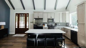 A modern kitchen with a central island, stainless steel appliances, and a large window. - Cedar Ridge Red River Gorge HotTub WiFi (Campton)