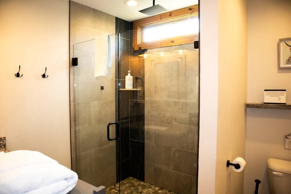 A modern bathroom with a glass-enclosed shower, a toilet, and a sink.