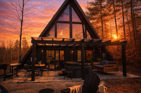 A cabin with a large glass front, outdoor seating, and a patio area.