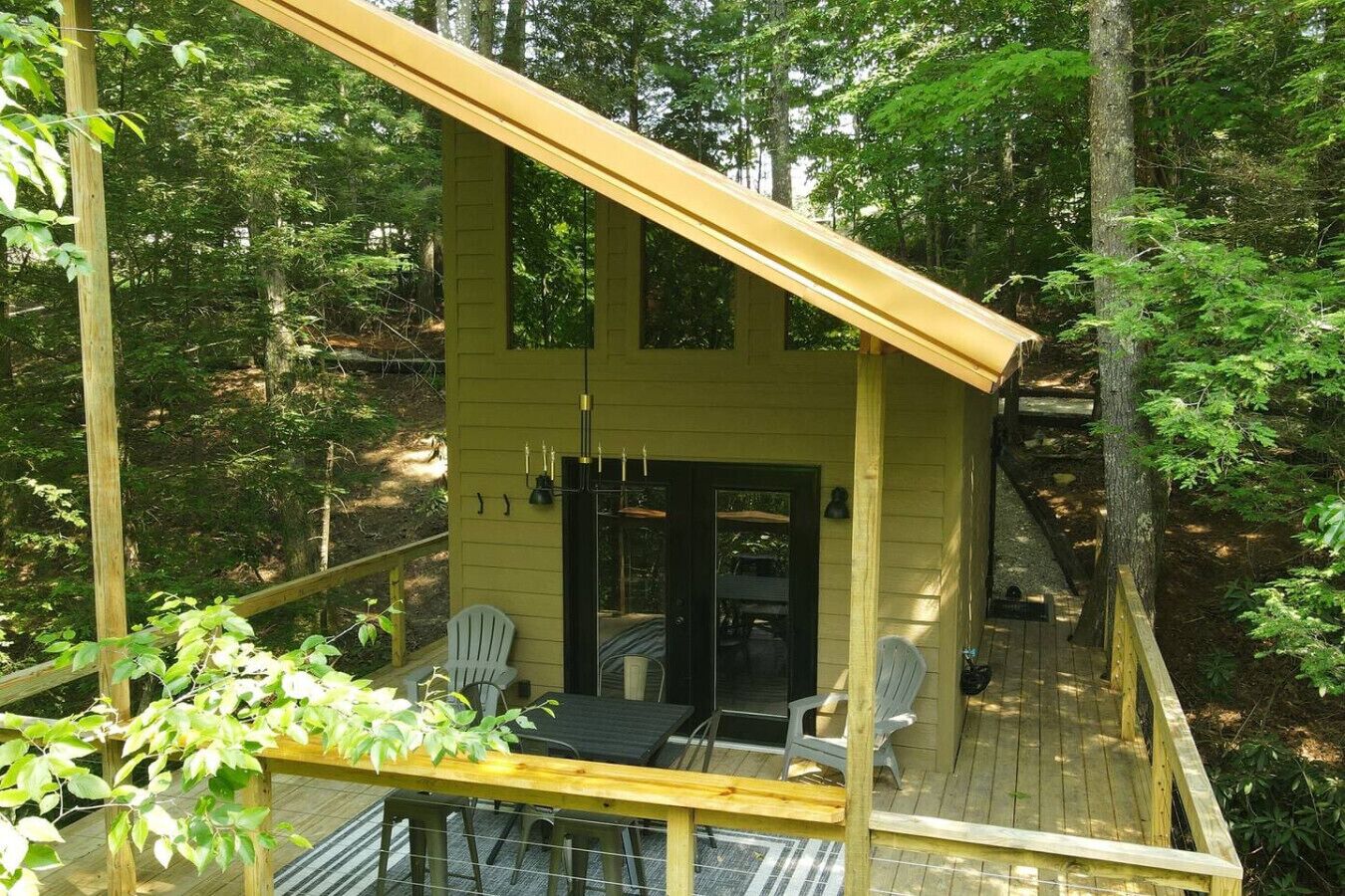 A wooden cabin with a deck, a dining area, and a black door.