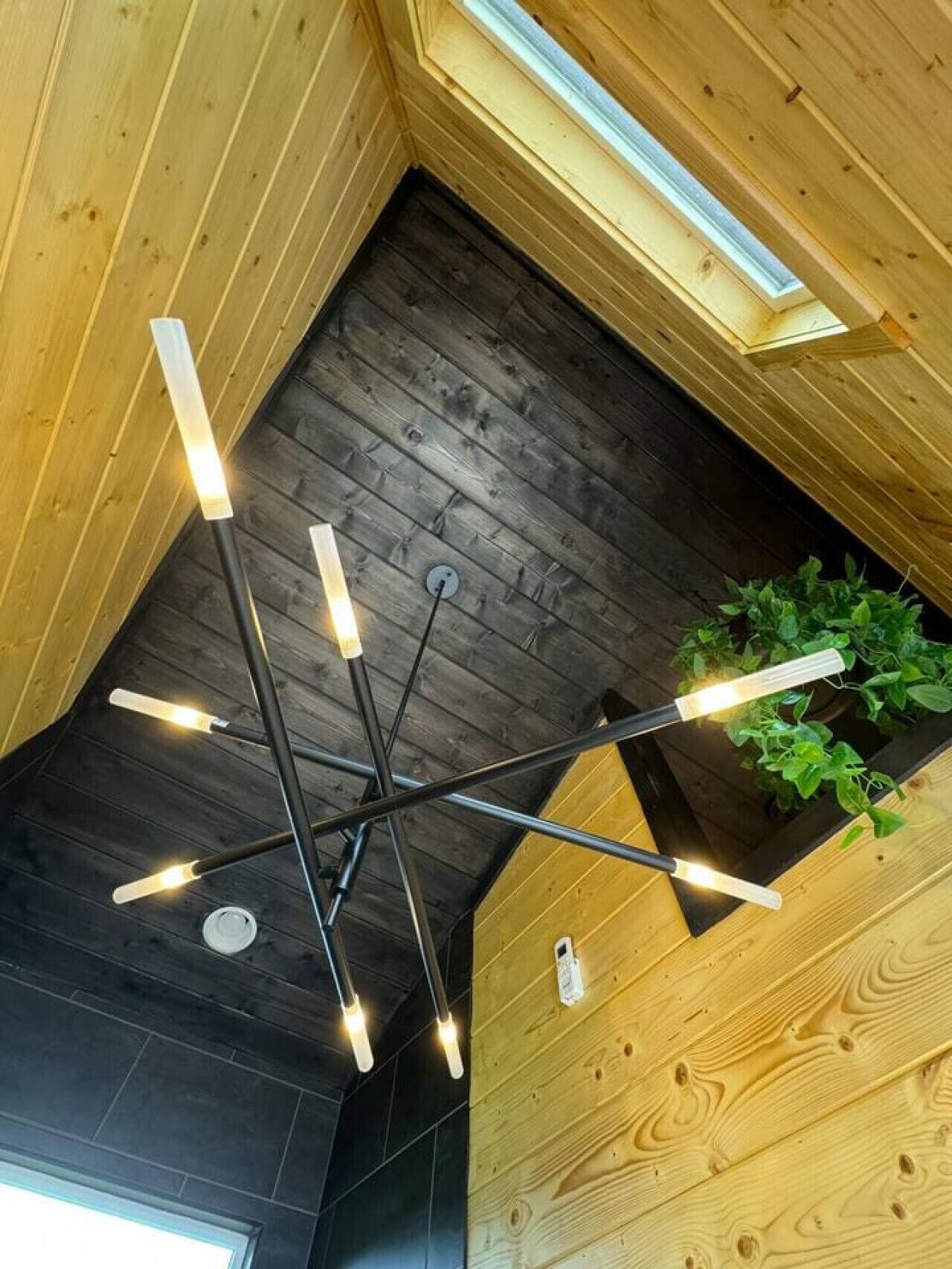 A modern interior with a wooden ceiling, a black floor, and a skylight.