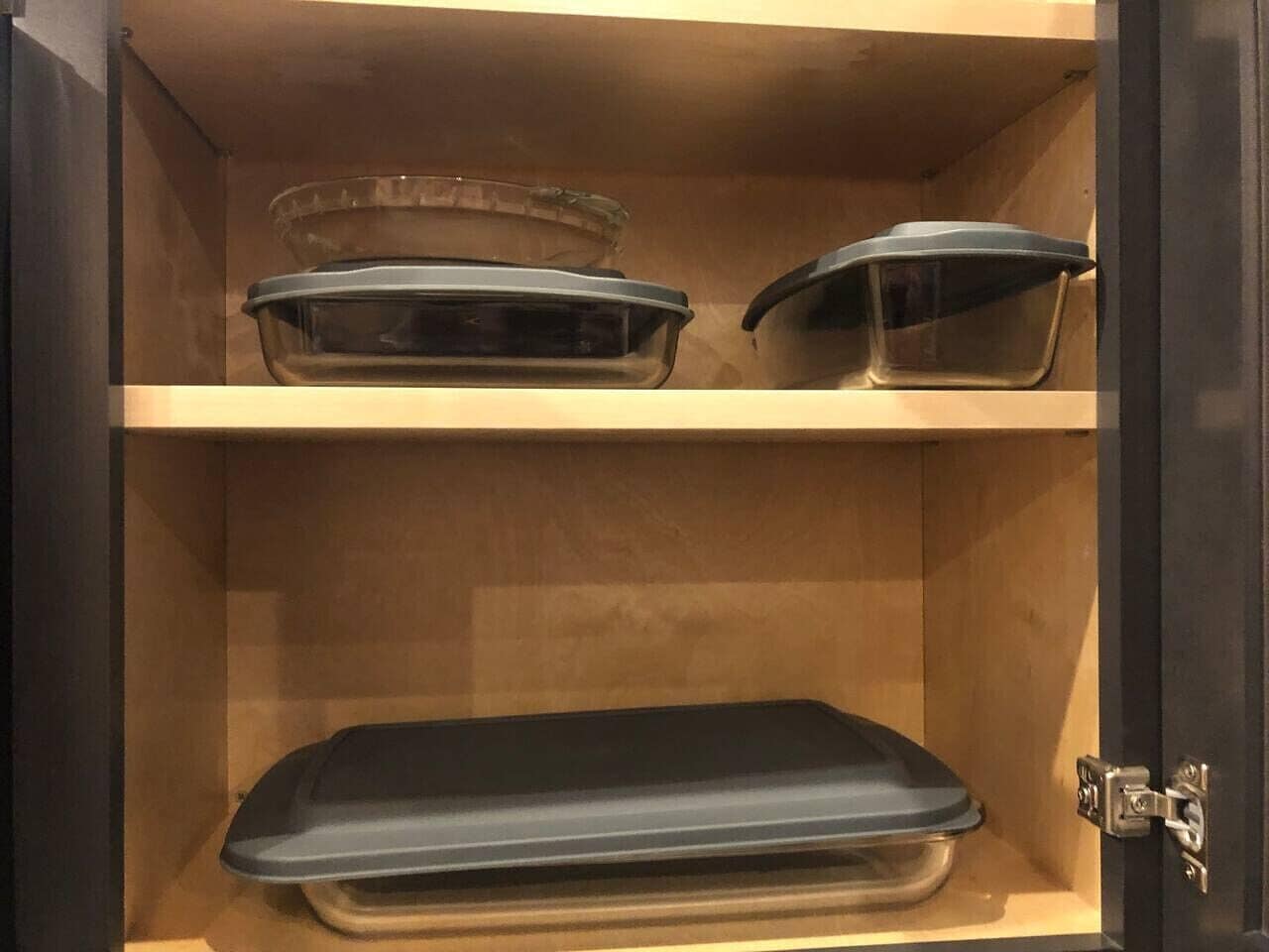 A cabinet with three glass baking dishes on shelves.