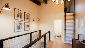 Een modern interieur met een houten trap, een gang met ingelijste foto’s, en een minimalistisch ontwerp.