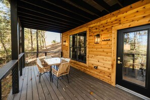A wooden cabin with a covered porch, a dining table with chairs, and large windows. - White Pine, Red River Gorge (Campton)