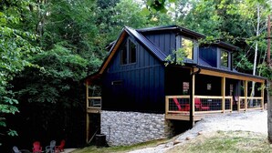 A cabin with a stone foundation, wooden deck, and a covered porch.