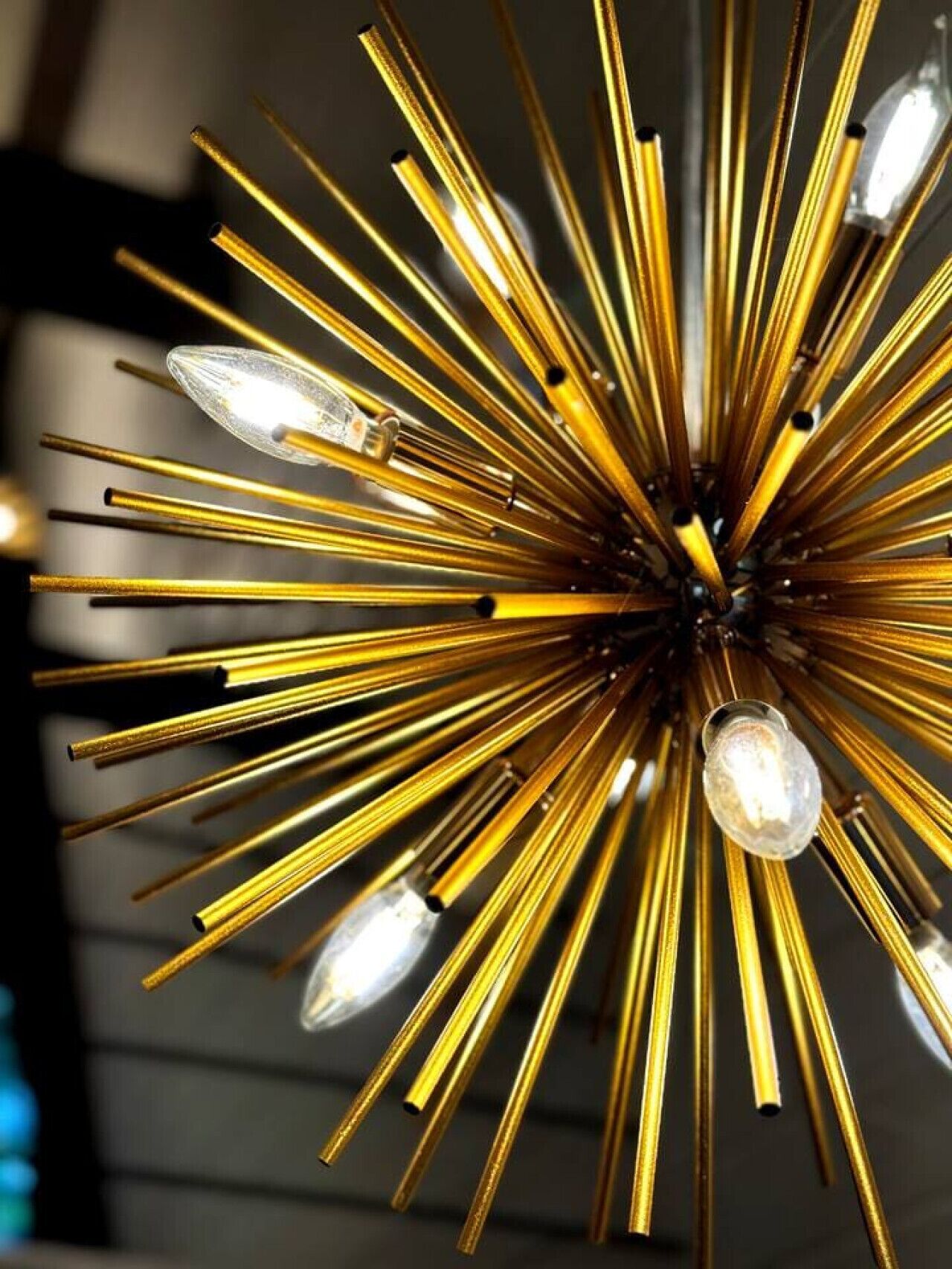 A chandelier with multiple light bulbs and golden metallic arms.