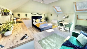 A compact, modern apartment with a kitchenette, a bed, a dining area, and a small office space.