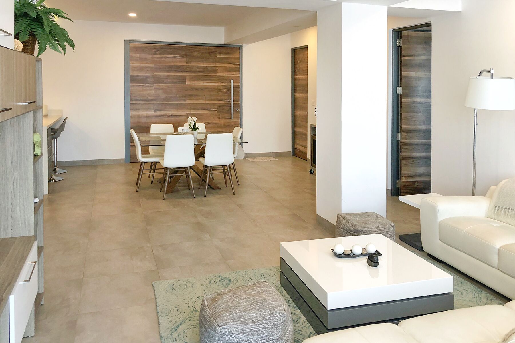 A modern living room with a white sofa, a coffee table, and a dining area with a glass table and chairs.
