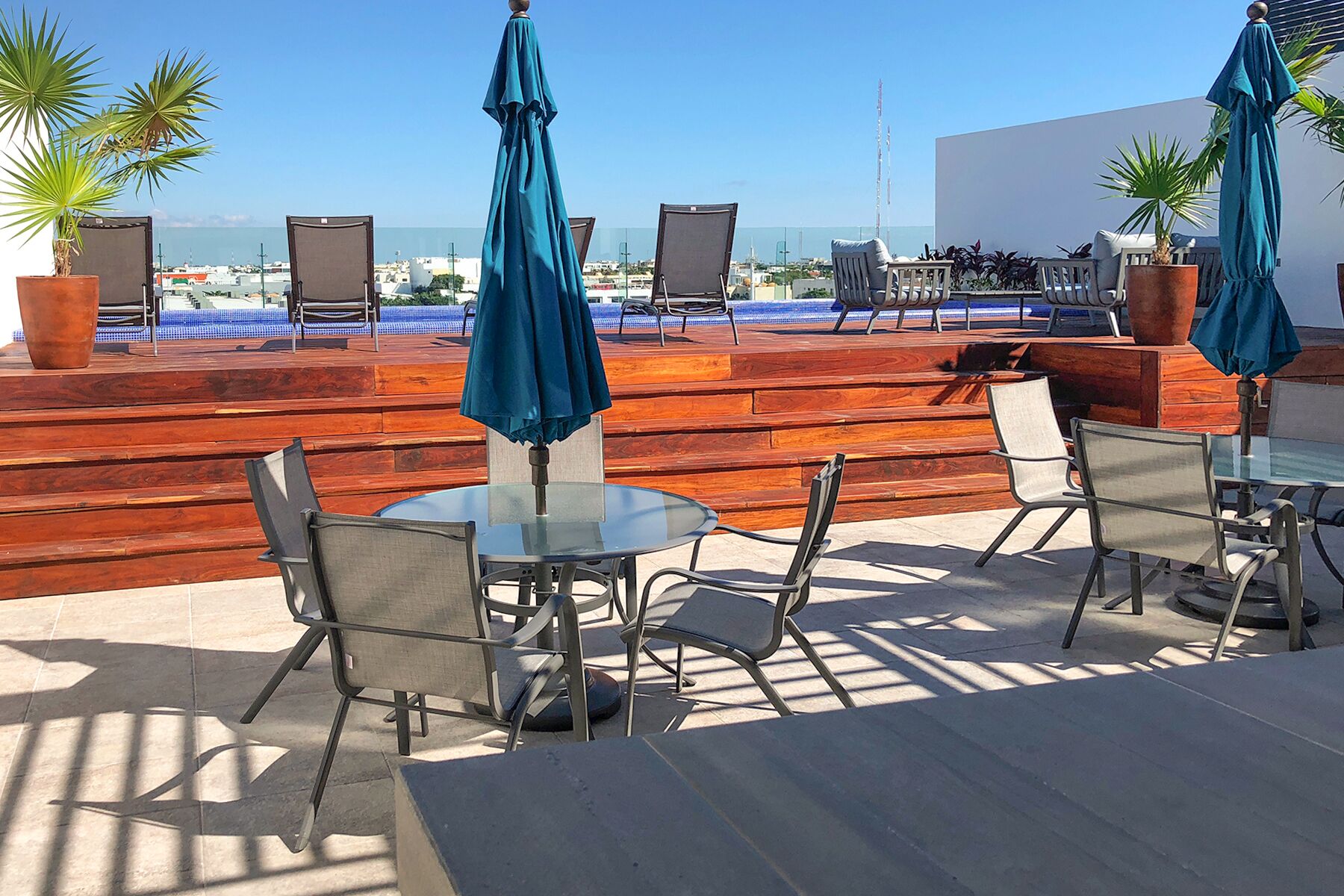An outdoor seating area with tables and chairs, umbrellas, and potted plants.