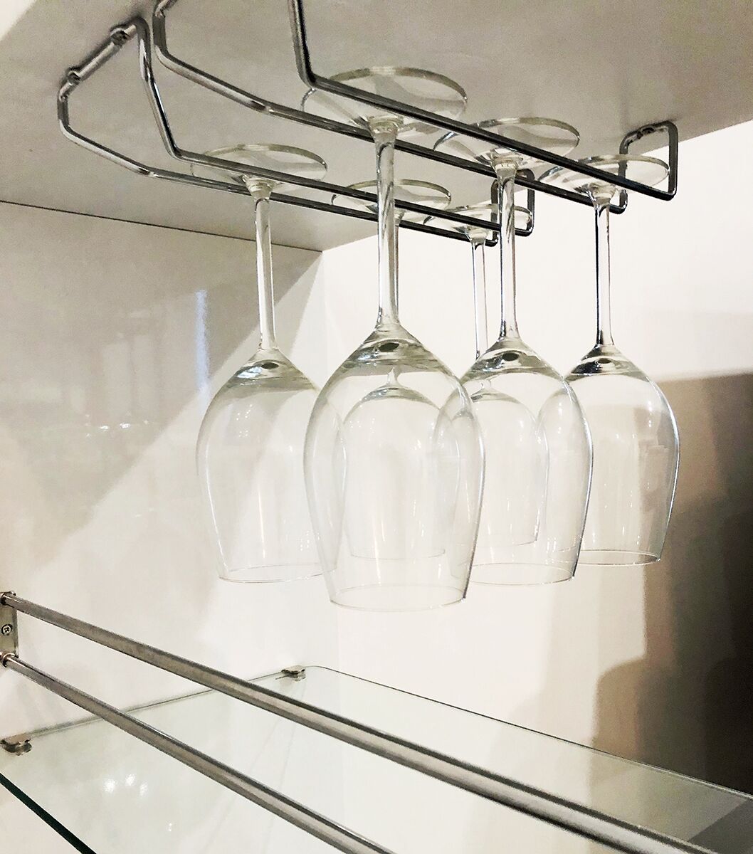 A wine rack with four wine glasses hanging from it.