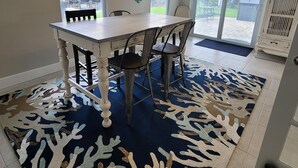 A dining area with a table and chairs, a patterned rug, and artwork on the walls. - Waterfront gulf access retreat in coveted SW cape. Bring your boat!  (Cape Coral)