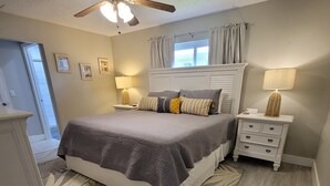 A bedroom with a bed, nightstands, a ceiling fan, and a window with curtains. - Waterfront gulf access retreat in coveted SW cape. Bring your boat!  (Cape Coral)