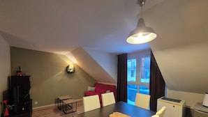 Eine moderne Lofts-Wohnung mit Essbereich, einem roten Sofa, einem kleinen Tisch und einer Küchenzeile.