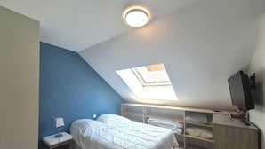 Ein Schlafzimmer mit Oberlicht, Bett, Nachttisch und Fernseher.