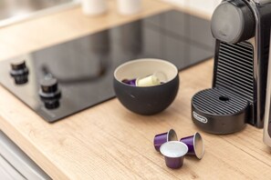 A kitchen counter with a coffee maker, a bowl, and a few cups.