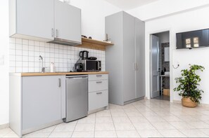 A modern kitchen with grey cabinets, a dishwasher, a coffee maker, and a TV mounted on the wall.