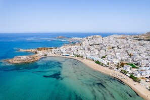 A coastal cityscape with a clear blue sea, sandy beaches, and densely packed white buildings. - Makares Downtown Apartments (Naxos)
