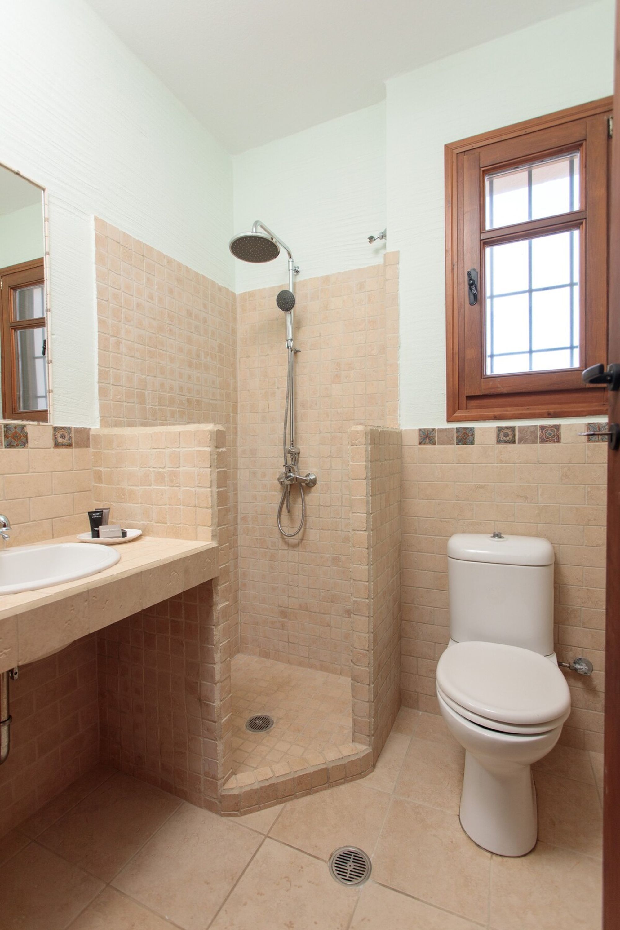 A bathroom with a shower, toilet, sink, and a window.