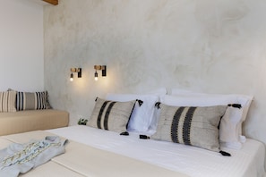 A bedroom with a bed, pillows, a bedside table, and wall-mounted lights.