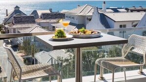 A balcony with a table set for dining, overlooking a coastal cityscape. - Guest Favorite Beach Beauty with Bunks SLPS 8! (Inlet Beach)