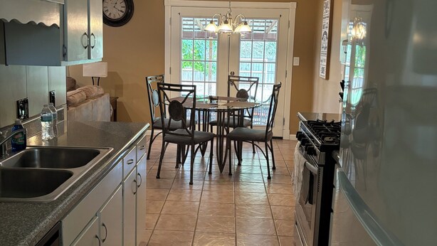A kitchen with a dining table, chairs, a refrigerator, a stove, and a sink.