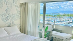 A bedroom with a large bed, a view of a marina, and a balcony with wicker furniture.