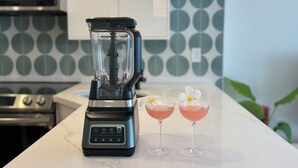 Una cocina con una licuadora, dos bebidas y un salpicadero decorado.