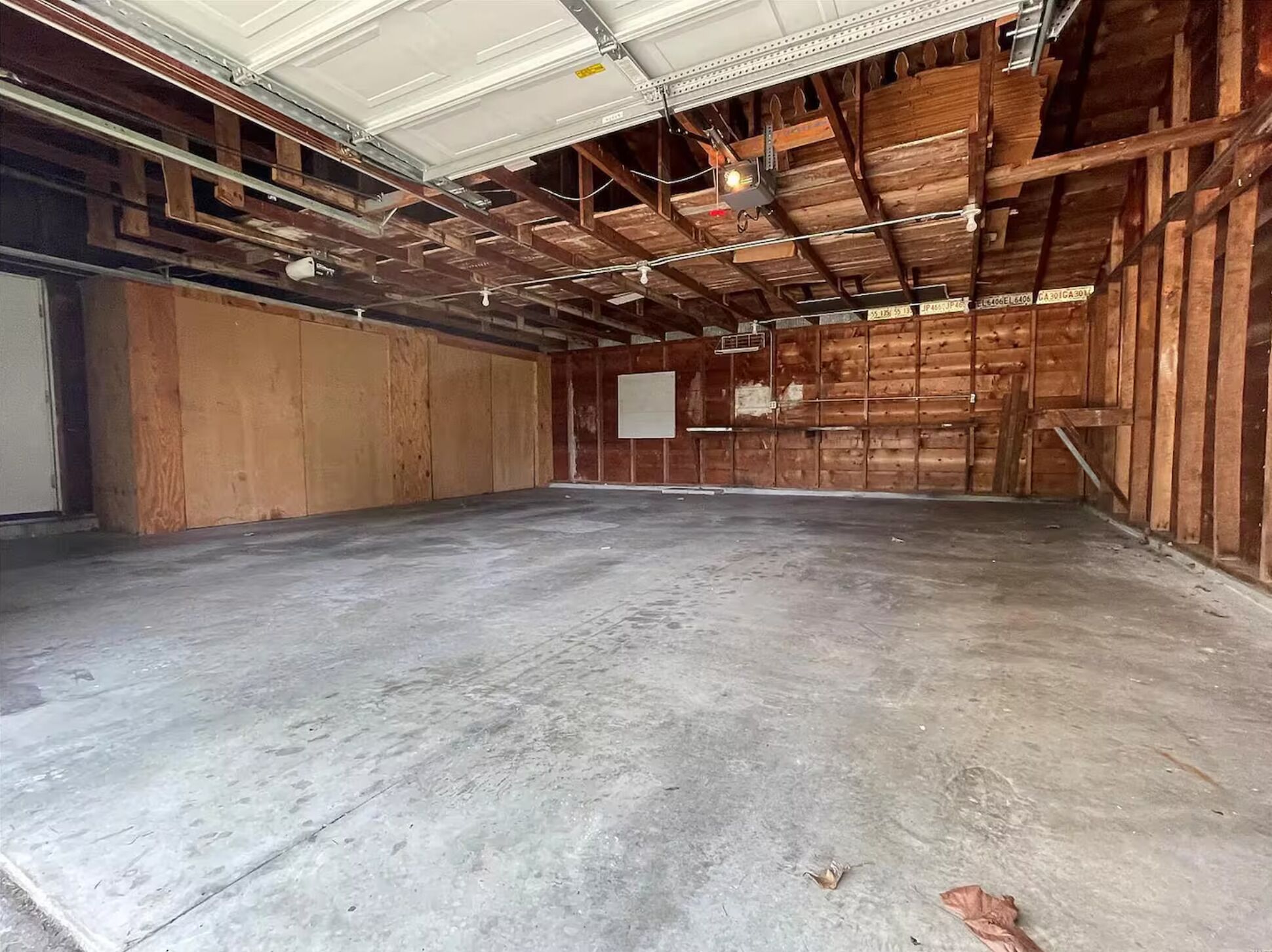 An empty warehouse with a concrete floor, wooden walls, and metal beams.