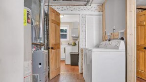 Un cuarto de lavandería con lavadora, secadora y sala de servicios con paneles eléctricos.