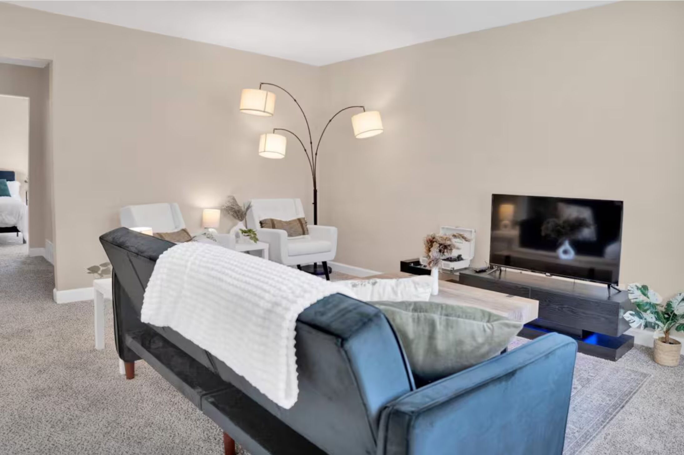 Een moderne woonkamer met een bank, twee fauteuils, een salontafel en een flatscreen televisie.