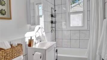 Un baño moderno con tocador blanco, ducha con ventana y bañera.