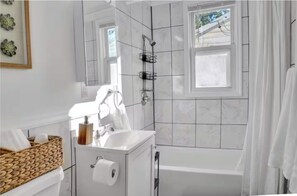 A modern bathroom with a white vanity, a shower with a window, and a bathtub. - Charming 2-bedroom house in amazing Belleville with AC, WiFi (Belleville)